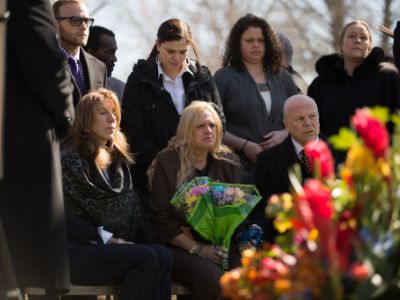 Mari Gilbert looks sad as she is sitting holding the flowers in her hand.